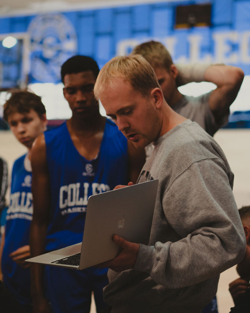 Alex Sarama showing his basketball team clips on an apple laptop. Corzek provide social media direction for Transforming Basketball.