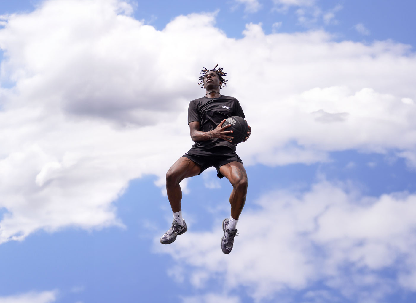 Basketball player in the clouds holding the ball whilst jumping. A picture taken by the Sports Media Agency Corzek.